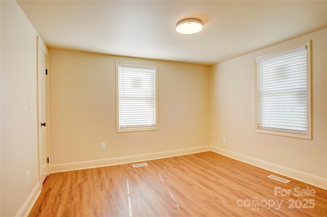 empty room with baseboards, light wood finished floors, and visible vents