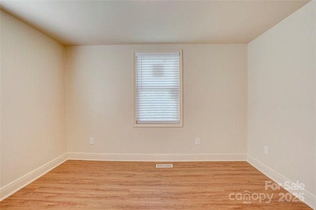 unfurnished room featuring baseboards, light wood-style flooring, and visible vents