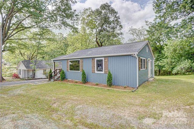 ranch-style house featuring roof with shingles and a front yard