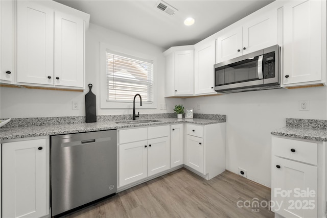3205 Morning Dr, Charlotte, NC 28208 - kitchen featuring visible vents, light stone counters, a sink, light wood finished floors, and appliances with stainless steel finishes