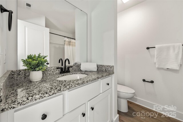 3205 Morning Dr, Charlotte, NC 28208 - full bathroom with vanity, toilet, baseboards, wood finished floors, and visible vents