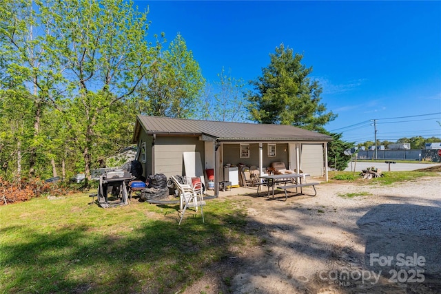 back of property with a yard and metal roof