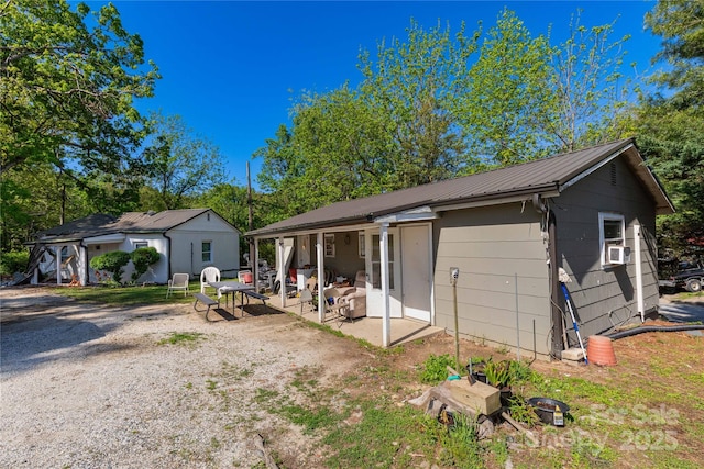 rear view of property featuring cooling unit, metal roof, and a patio area