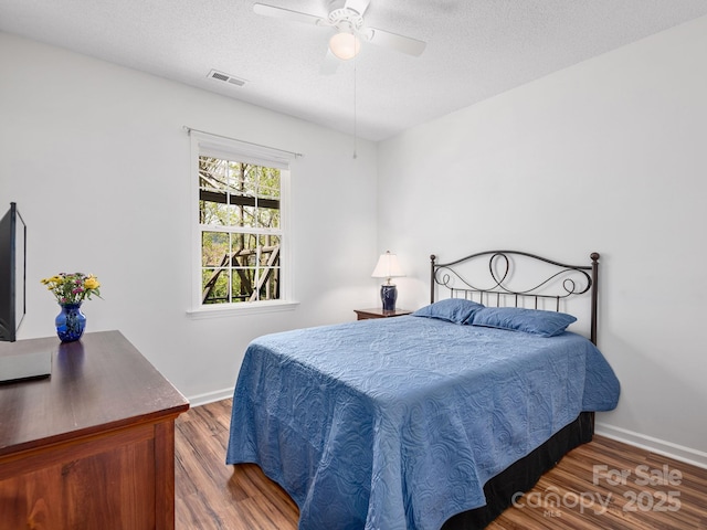 bedroom with wood finished floors, visible vents, and baseboards