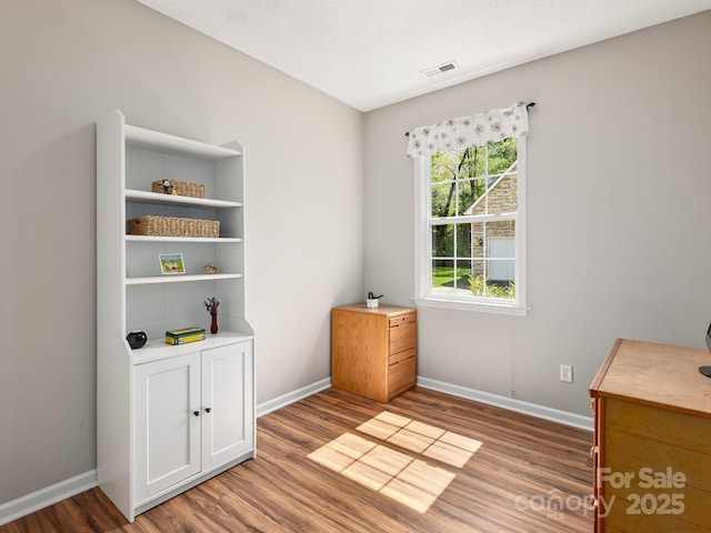 interior space featuring baseboards, visible vents, and wood finished floors