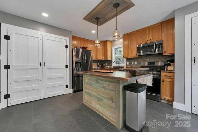 kitchen with tasteful backsplash, brown cabinetry, appliances with stainless steel finishes, dark countertops, and a sink
