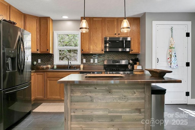 kitchen with a sink, stainless steel appliances, brown cabinetry, backsplash, and dark countertops