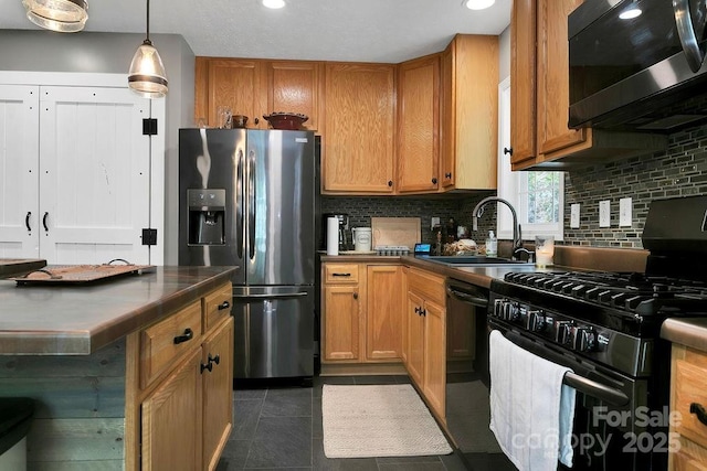 kitchen with black appliances, dark countertops, decorative backsplash, and a sink