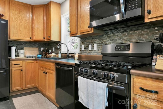 kitchen with a sink, appliances with stainless steel finishes, tile patterned floors, and tasteful backsplash