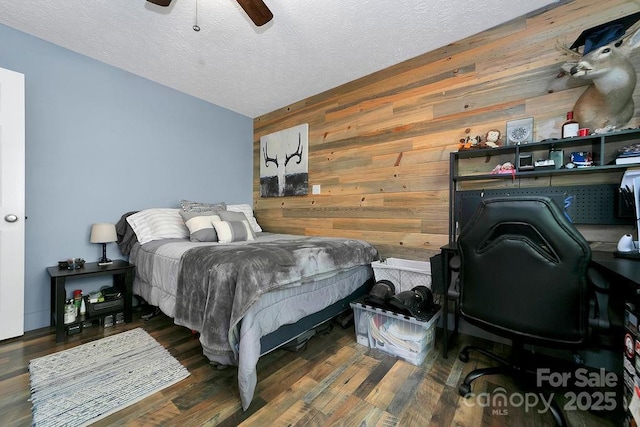 bedroom with wood finished floors, ceiling fan, wooden walls, and a textured ceiling