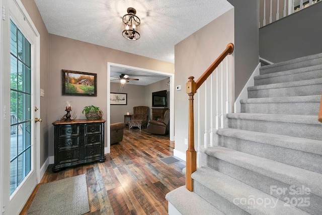 entryway featuring a textured ceiling, stairway, ceiling fan, baseboards, and wood finished floors