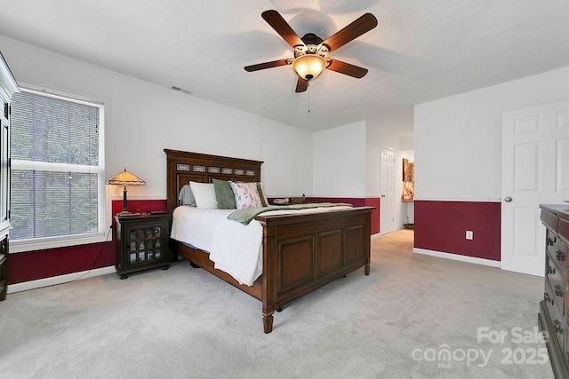 bedroom featuring a ceiling fan, a textured ceiling, light colored carpet, and baseboards