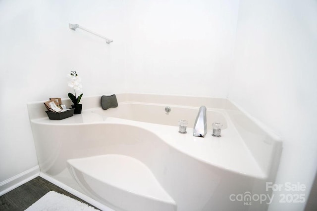 full bathroom featuring a bath and baseboards