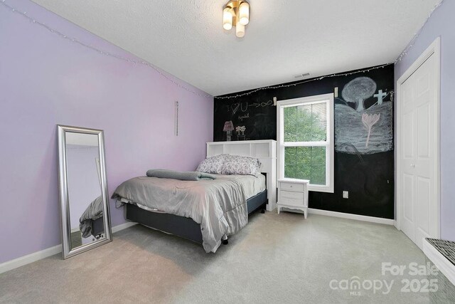 bedroom featuring visible vents, an accent wall, carpet floors, and baseboards