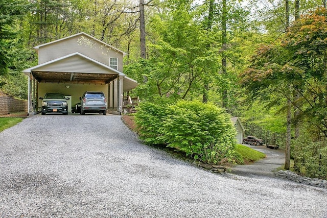 exterior space with a wooded view, driveway, and an attached carport