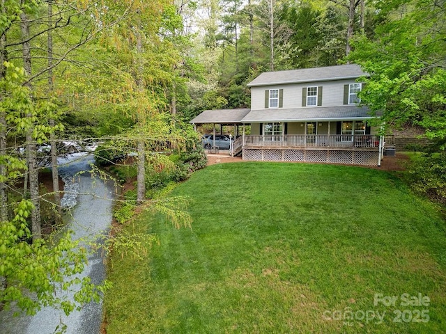 view of front of house featuring a wooded view, a front lawn, covered porch, and aphalt driveway