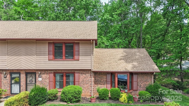 view of front of house featuring brick siding and roof with shingles