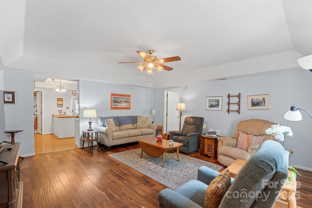 living room with baseboards, a raised ceiling, ceiling fan, and hardwood / wood-style flooring