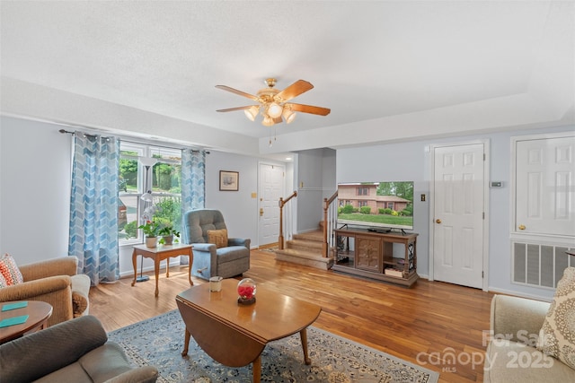 living room with ceiling fan, stairs, baseboards, wood finished floors, and visible vents