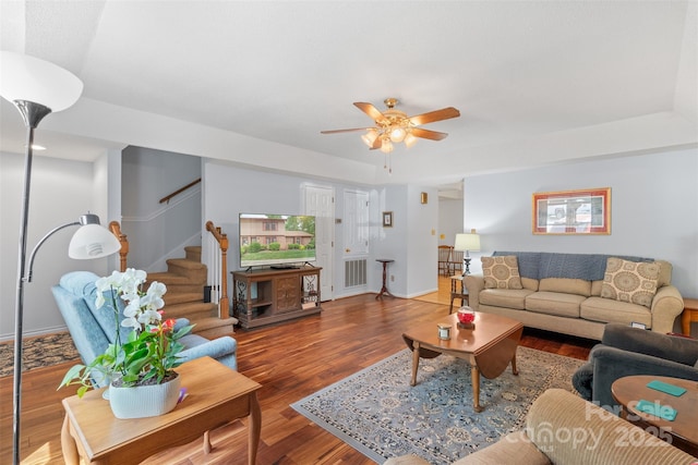 living area with visible vents, wood finished floors, baseboards, ceiling fan, and stairway