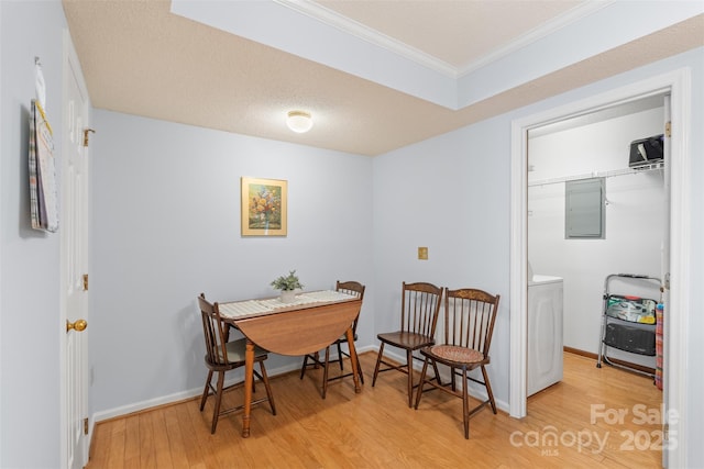 dining space featuring crown molding, washer / dryer, baseboards, light wood-type flooring, and electric panel