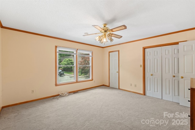 unfurnished bedroom featuring baseboards, ornamental molding, carpet, and ceiling fan