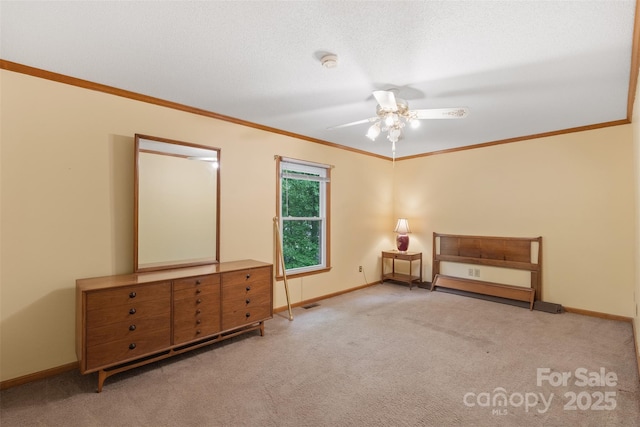 unfurnished bedroom featuring crown molding, baseboards, ceiling fan, and carpet flooring