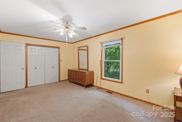 unfurnished bedroom featuring carpet flooring, ceiling fan, baseboards, visible vents, and a closet