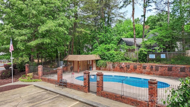 community pool featuring a patio, fence, and an outbuilding