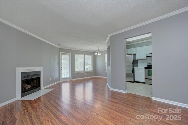 6510 Clavell Ln Unit B, Charlotte, NC 28210 - unfurnished living room with a fireplace with flush hearth, a textured ceiling, an inviting chandelier, light wood-type flooring, and ornamental molding