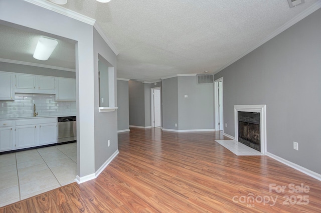6510 Clavell Ln Unit B, Charlotte, NC 28210 - unfurnished living room featuring light wood-style flooring, visible vents, a textured ceiling, a fireplace with flush hearth, and crown molding