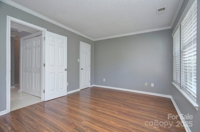 6510 Clavell Ln Unit B, Charlotte, NC 28210 - unfurnished bedroom with ornamental molding, a textured ceiling, wood finished floors, and visible vents