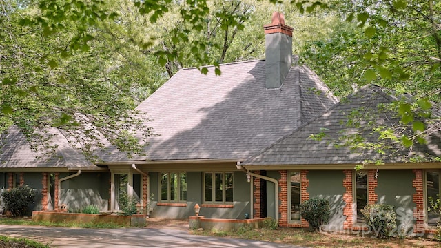 view of front facade featuring a shingled roof and a chimney