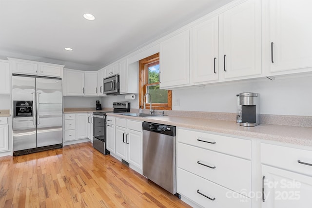 kitchen with recessed lighting, a sink, stainless steel appliances, white cabinetry, and light countertops