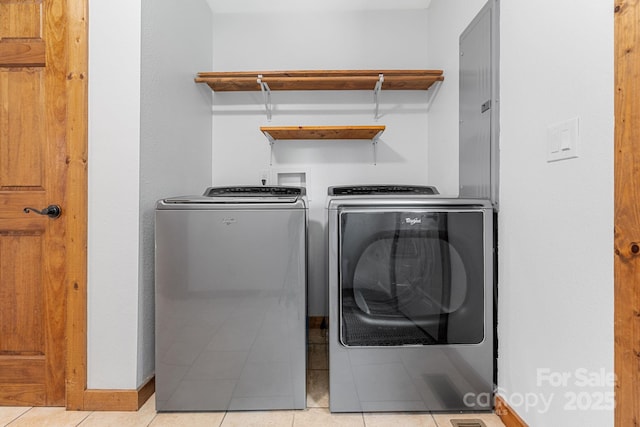 laundry room featuring baseboards, light tile patterned floors, separate washer and dryer, and laundry area