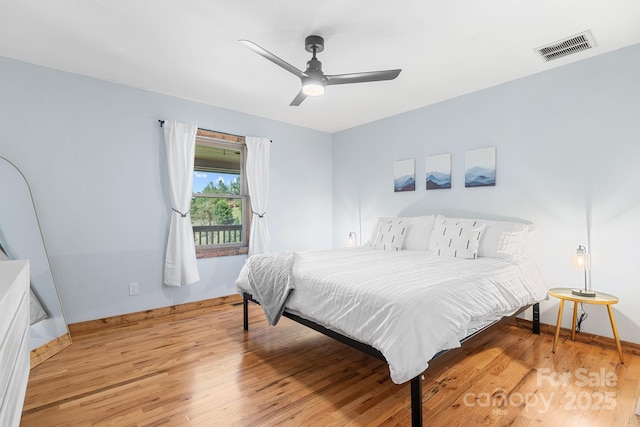 bedroom with a ceiling fan, visible vents, wood finished floors, and baseboards