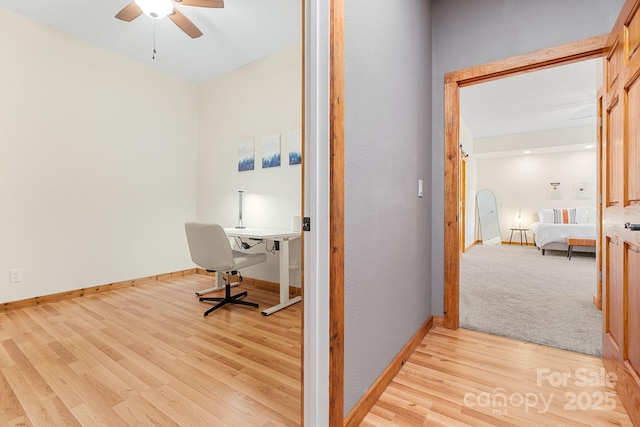 home office with a ceiling fan, baseboards, and light wood-type flooring