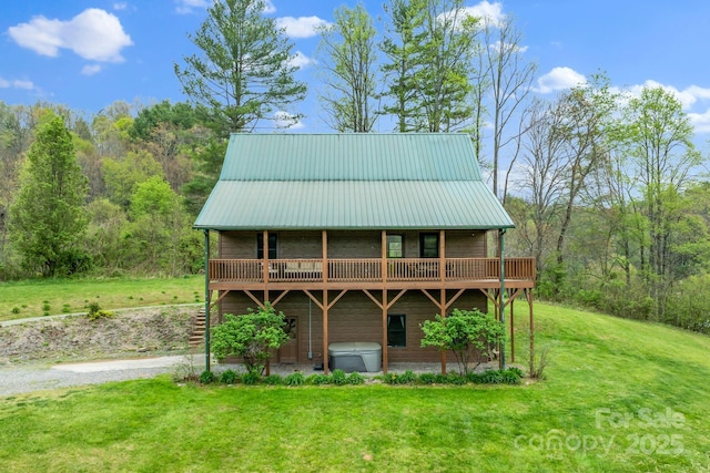 rear view of property with metal roof, a lawn, and a wooden deck