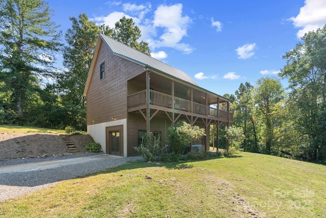view of front of property with metal roof, gravel driveway, and a front lawn