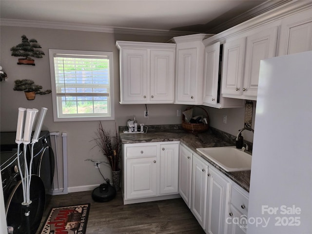 kitchen featuring a sink, baseboards, white cabinets, freestanding refrigerator, and dark wood-style floors