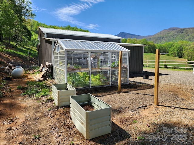 view of greenhouse with fence and a mountain view