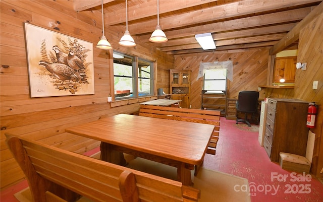 dining room with wood walls, beam ceiling, and wood finished floors