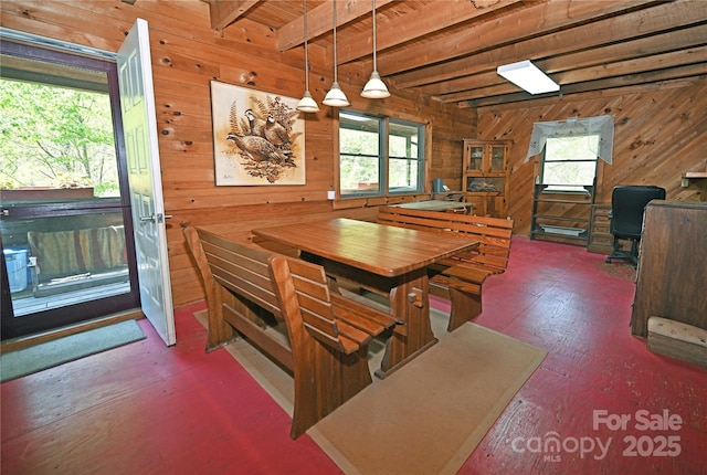 dining space featuring beamed ceiling, wood walls, and wood finished floors