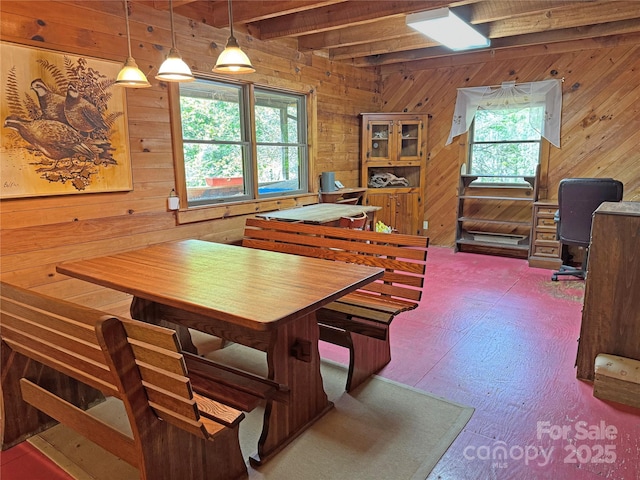 dining space with plenty of natural light, wood walls, and beamed ceiling