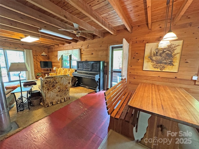 dining area featuring wood walls, wood ceiling, ceiling fan, and beam ceiling