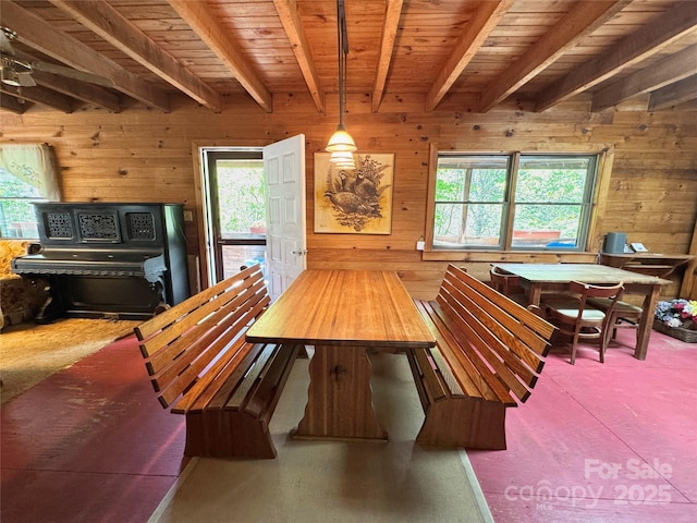 dining area featuring wood walls, beam ceiling, and a healthy amount of sunlight