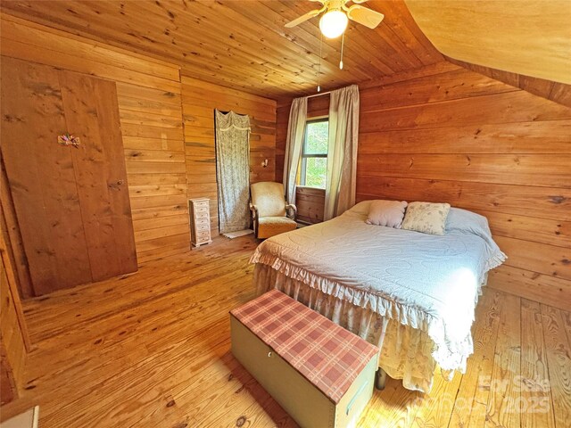 bedroom with ceiling fan, wooden ceiling, wood-type flooring, lofted ceiling, and wooden walls