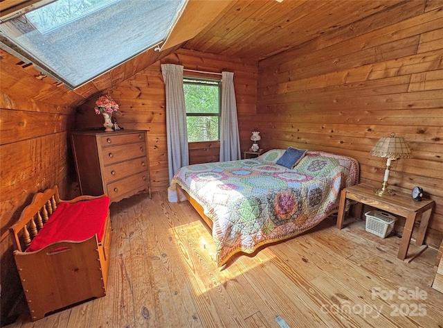 bedroom featuring wood walls, vaulted ceiling with skylight, hardwood / wood-style flooring, and wooden ceiling