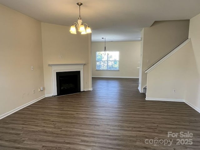 unfurnished living room featuring dark wood-style floors, an inviting chandelier, a fireplace with flush hearth, stairway, and baseboards
