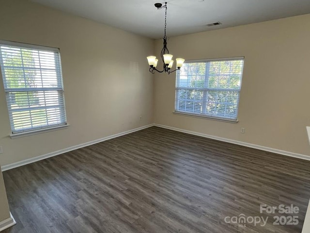 spare room featuring dark wood-style floors, visible vents, an inviting chandelier, and baseboards
